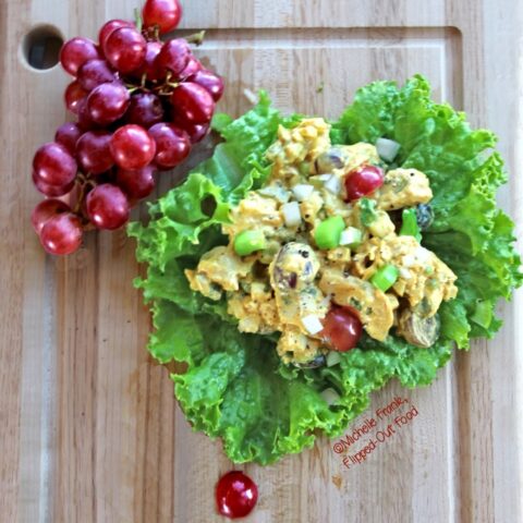 Curried Chicken Salad on lettuce leaves with a bunch of grapes. An easy party or picnic recipe, great in lettuce or flatbread wraps—or on buttery croissants. #currychickensalad #curriedchickensalad #partyfood #picnicfood #chickensalad #flippedoutfood #healthyeating via @FlippedOutFood