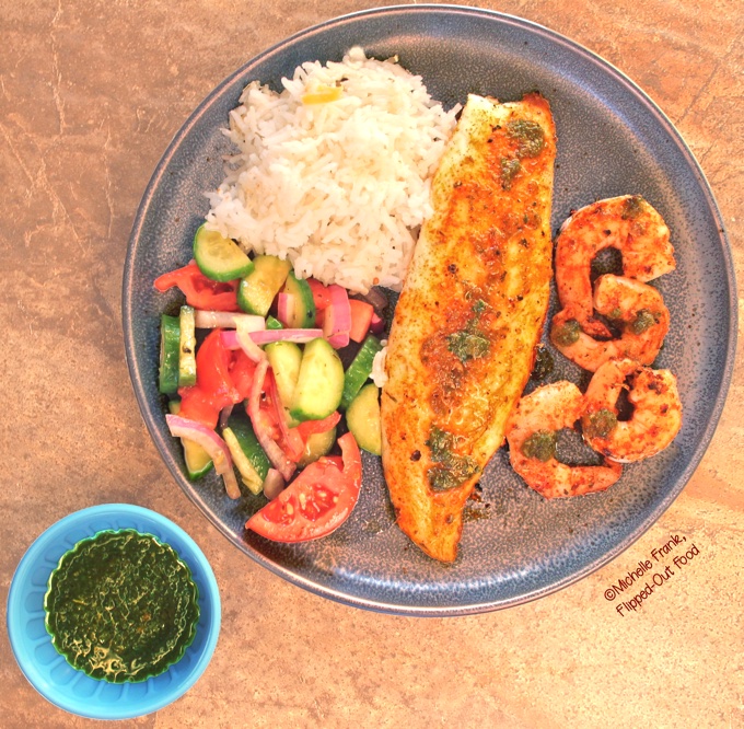 A seafood dinner with Angry Jerk Sauce: Cajun-spiced tilapia and shrimp sprinkled in the jerk sauce, with a side of cucumber, onion, and tomato salad and coconut habañero rice.