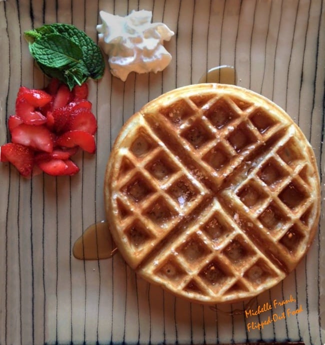 Best-ever waffles: beautiful waffle served on a striped plate with mint, strawberries, and whipped cream