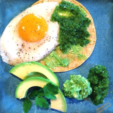 salsa verde huevos rancheros with guacamole, cilantro, and avocado slices