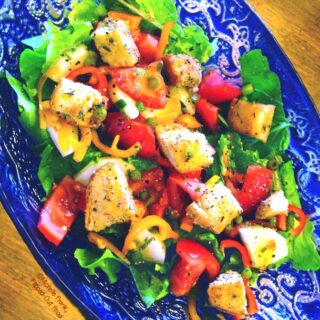 easy vinaigrette dressing in ornate blue bowl with homemade croutons and garlic scapes