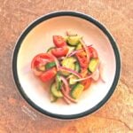 Cucumber-Tomato-Onion Salad on a white, ceramic plate with a green rim.
