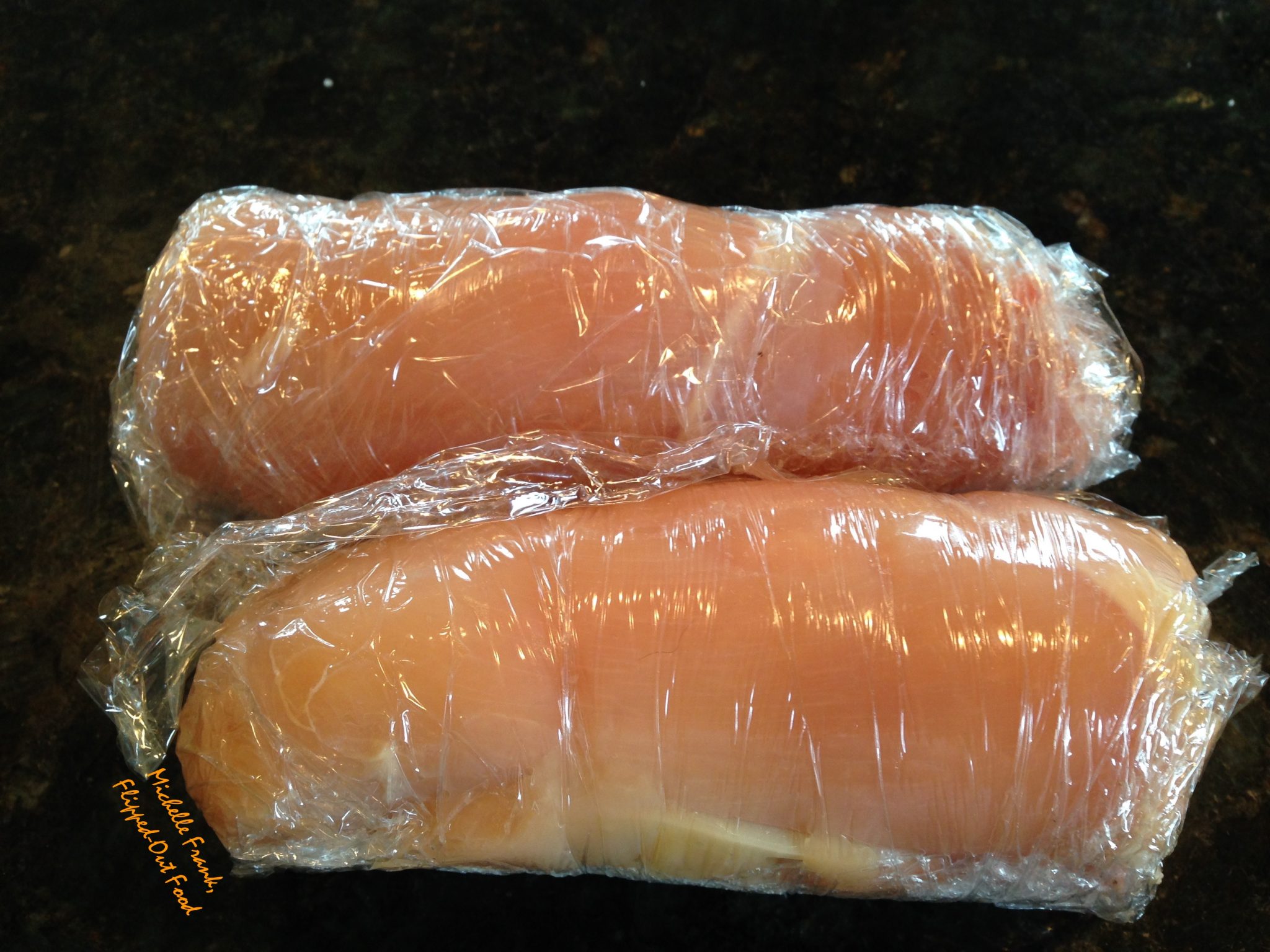 The rolled up work-ahead chicken rollatini wrapped in plastic, ready to go into the refrigerator.