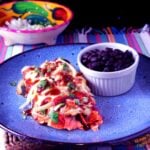 red enchiladas or chilaquiles serving with black beans