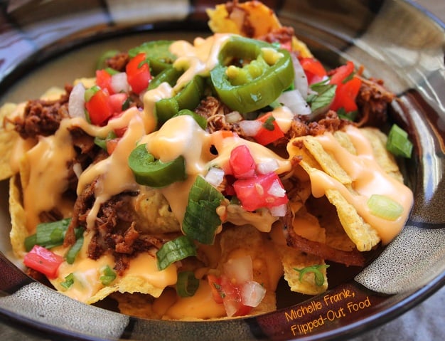 Close up side view of perfect loaded nachos in a bowl.