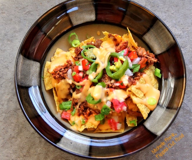 top view of perfect loaded nachos serving in a brown bowl.