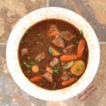 This is a heaping serving of Make-Ahead Irish Guinness Stew sprinkled with parsley. The rich, complex broth is the result of beef slowly simmering in Guinness Stout, along with a few other flavor-building hacks. |Irish Food | Comfort Food | Guinness Stew | Beef Stew | Lamb Stew