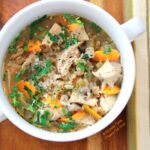 Close up of barley chicken & vegetable soup with striped napkin