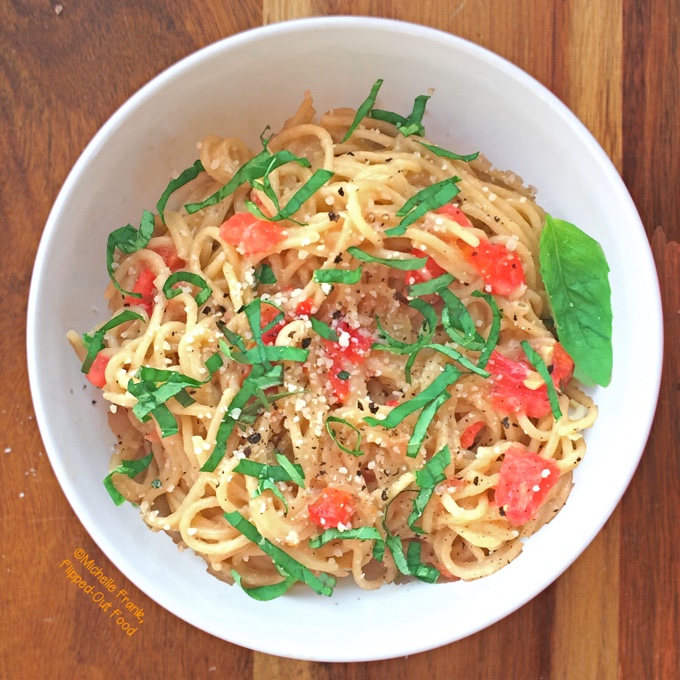 Easy garlic-tomato-basil pasta serving on wood background
