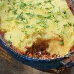 Guinness-Colcannon Shepherd Pie with a serving scooped out. A perfect Irish dish for Saint Patrick's Day and comfort food at its best. #saintpatricksday #stpaddysday #irishfood #comfortfood #shepherdspie #colcannon #guinness #lamb via @flippedoutfood