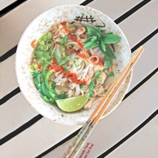Slow-cooker Rotisserie Chicken Pho Ga, top view of a bowl loaded up with herbs, jalapenos, scallions, and sriracha. #vietnamesefood #phoga #pho #phonoodlesoup #vietnamesechickennoodlesoup @FlippedOutFood