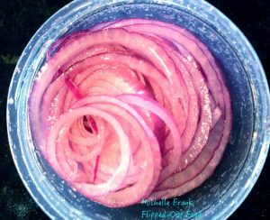 Easy Pickled Red Onion in a serving dish and storage jar, sitting on a rustic table. A must-have garnish for a variety of dishes, from Mexican to Asian and everything in between! #garnish #relish #condiment #pickledredonion #flippedoutfood @FlippedOutFood