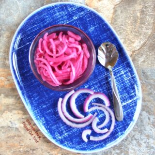 Easy Pickled Red Onion in a serving dish and storage jar, sitting on a rustic table. A must-have garnish for a variety of dishes, from Mexican to Asian and everything in between! #garnish #relish #condiment #pickledredonion #flippedoutfood @FlippedOutFood