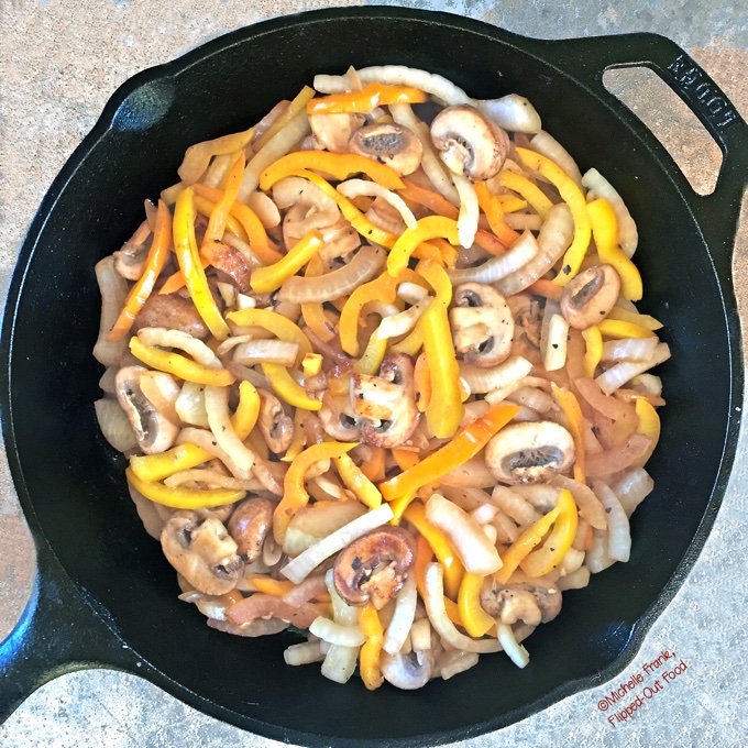 Overhead view of mushroom onion and peppers sauteed in cast iron skillet.