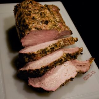 Herb-Roasted Rack of Pork sliced into huge chops on a cutting board.