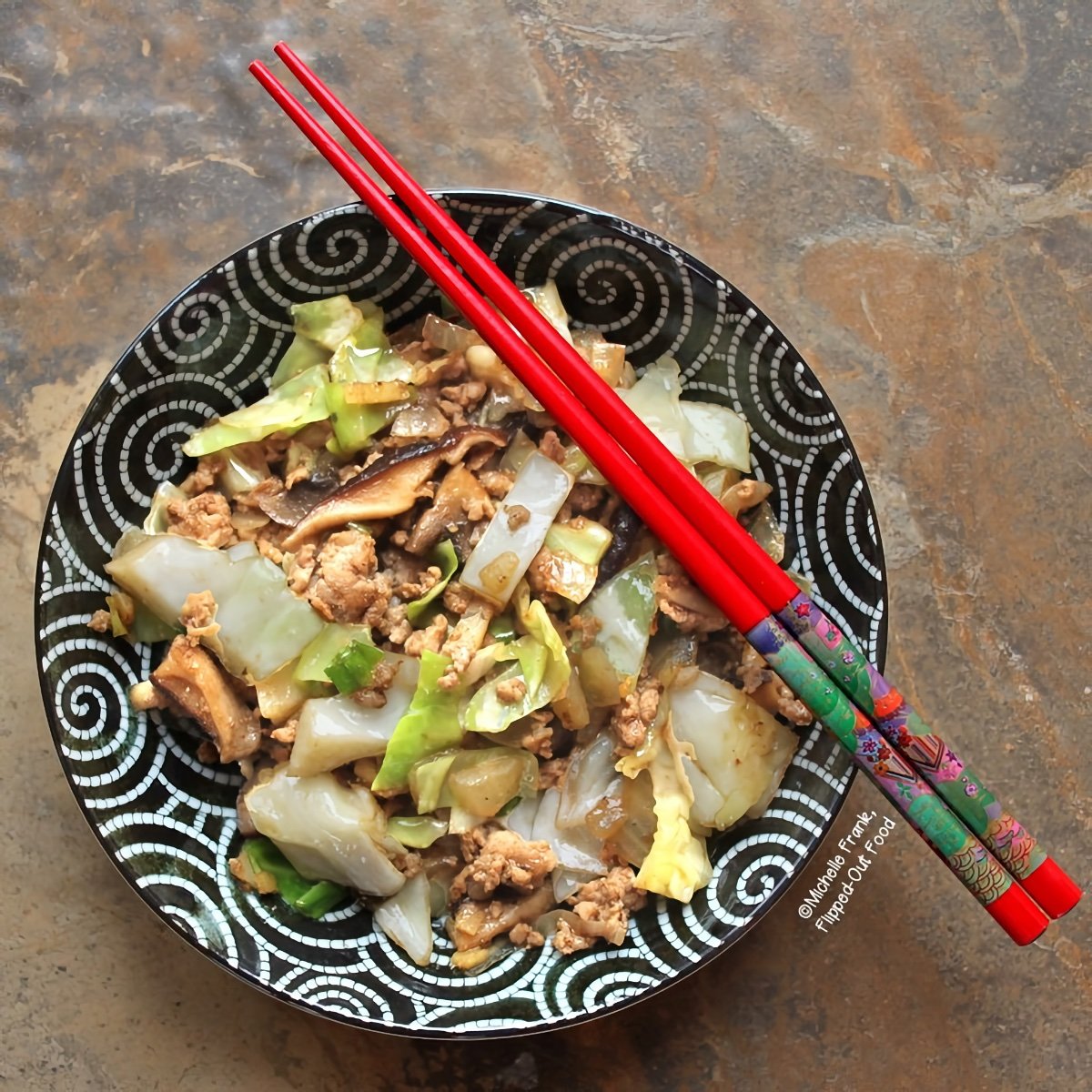 Overhead view of a serving of Inside-Out Egg Roll Bowl with a pair of colorful chopsticks sits atop the black and white oriental bowl.