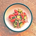 Cucumber-Tomato-Onion Salad on a white, ceramic plate with a green rim.