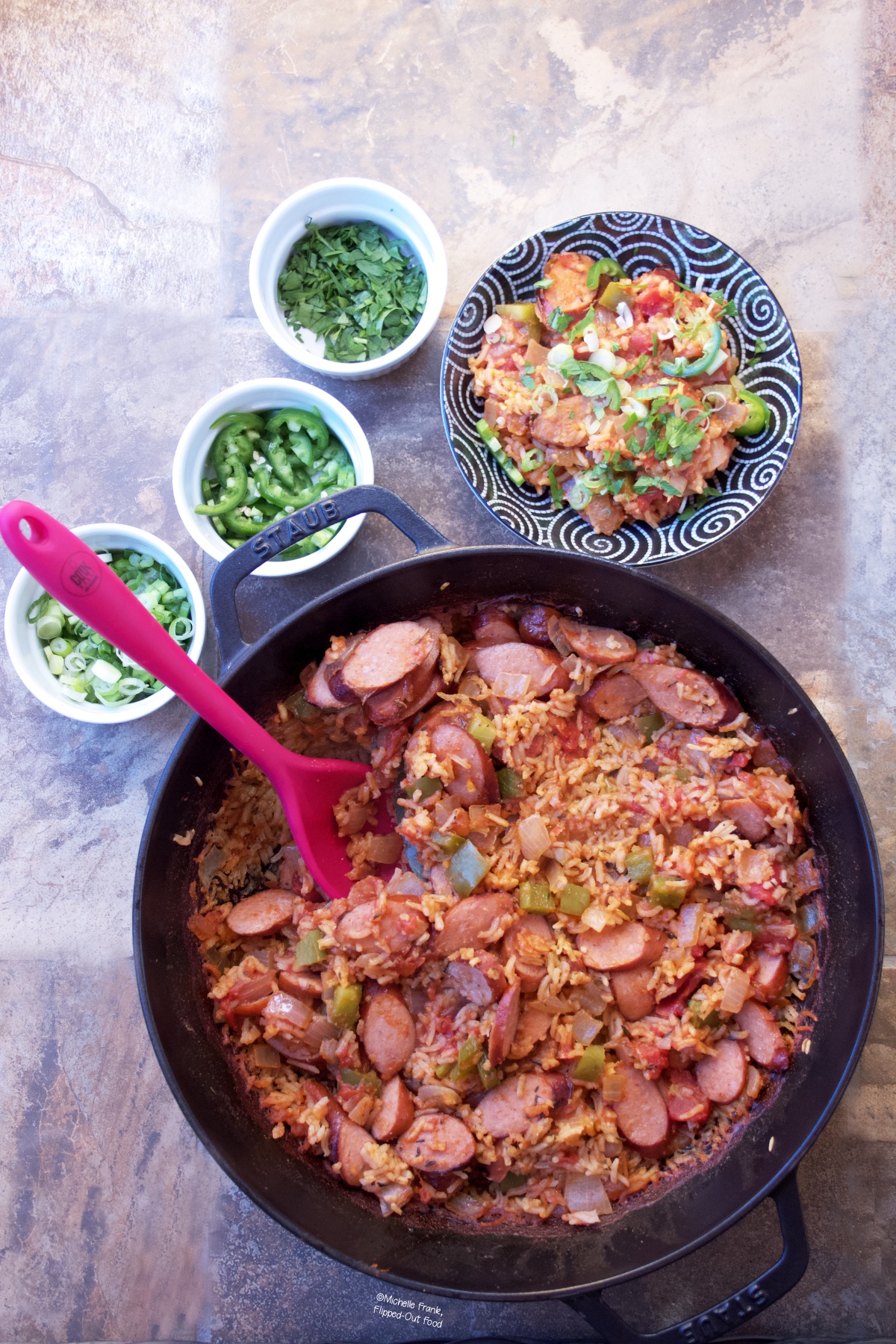 Cajun Sausage-Rice Skillet:  A bowl with a serving of the sausage and rice, with ramekins of scallions, jalapenos, and parsley sitting behind the skillet.