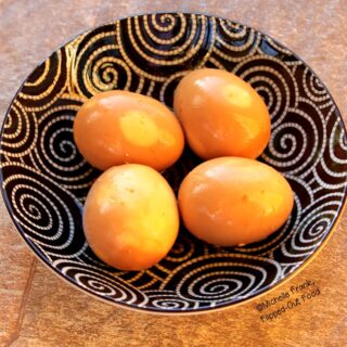 4 Soy-Miso Marinated Ramen Eggs in a decorative black and white bowl. The marinade has turned the eggs a deep, golden brown.