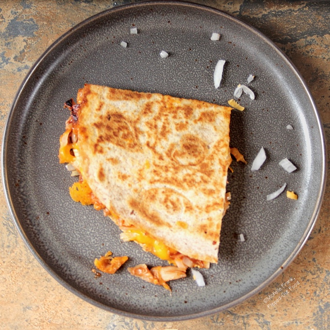 Top-down view of BBQ Chicken Quesadillas on a gray plate with a sprinkling of onions.