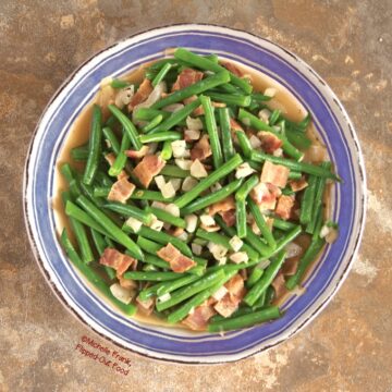 Overhead view of Green Beans with Bacon and Onions in a blue-rimmed bowl.