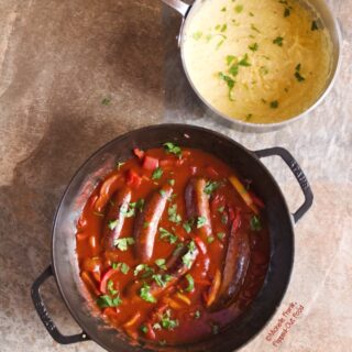Overhead view of the finished Sausage-Pepper Ragu with Polenta, sprinkled with chopped parsley and ready to serve.