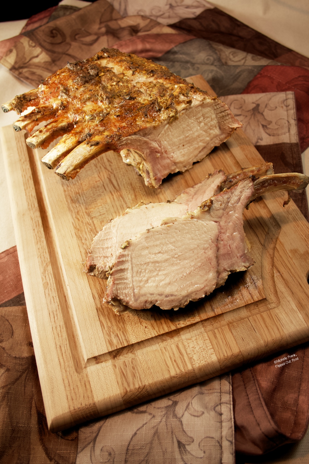 Herb-Roasted Rack of Pork on a cutting board with two gigantic chops sliced off.