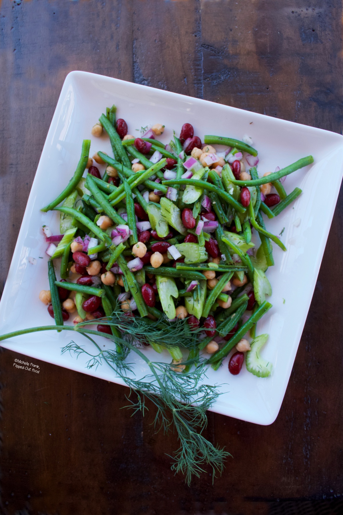 Tangy 3-Bean Salad on a white serving dish with a sprig of dill.