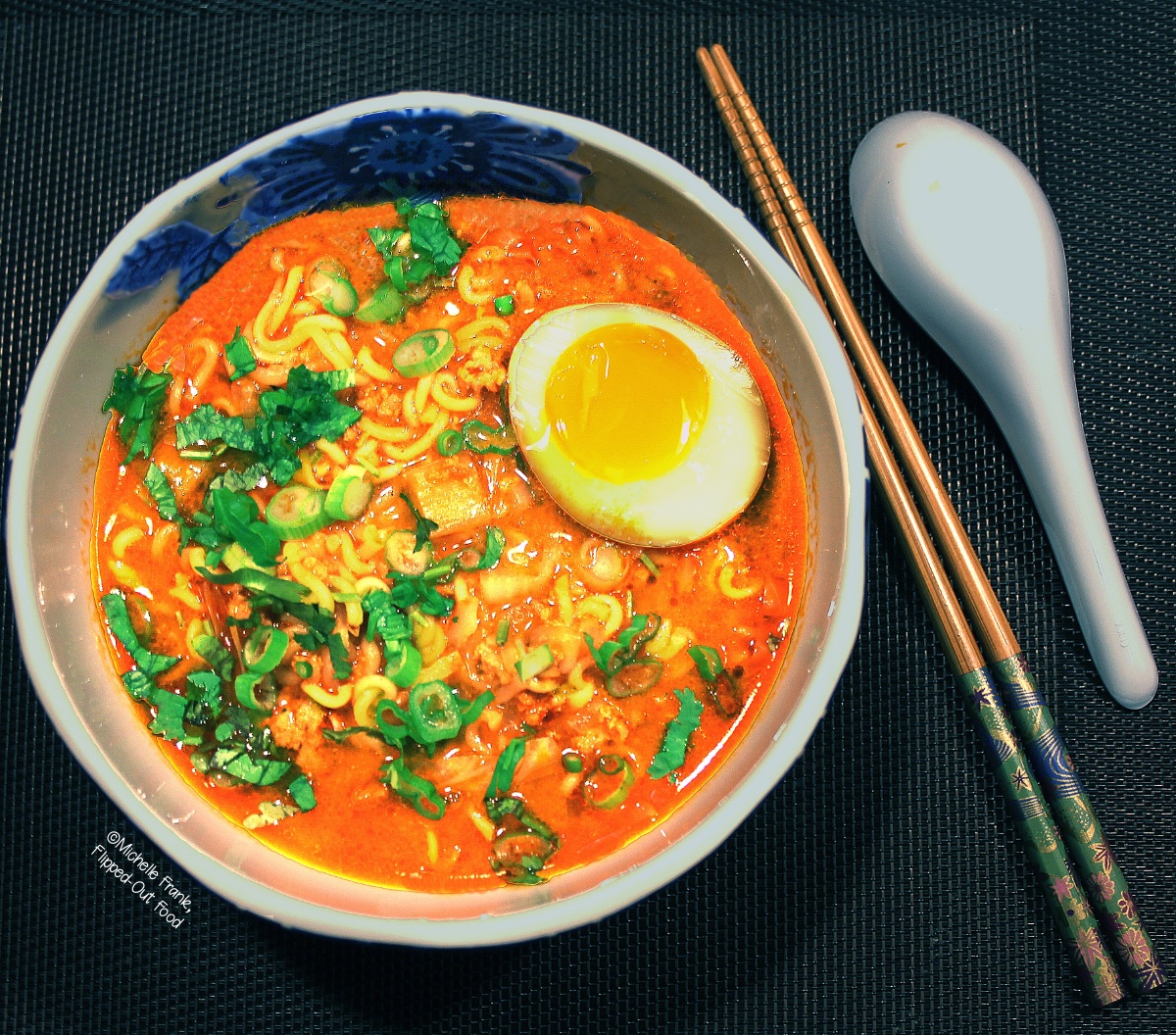 Easy Soups for Fall: Pork-Miso Ramen Soup with Soy-Marinated Egg. The soup is topped with half of the marinated egg and sliced scallions. A pair of chopsticks and a spoon sit next to the bowl.