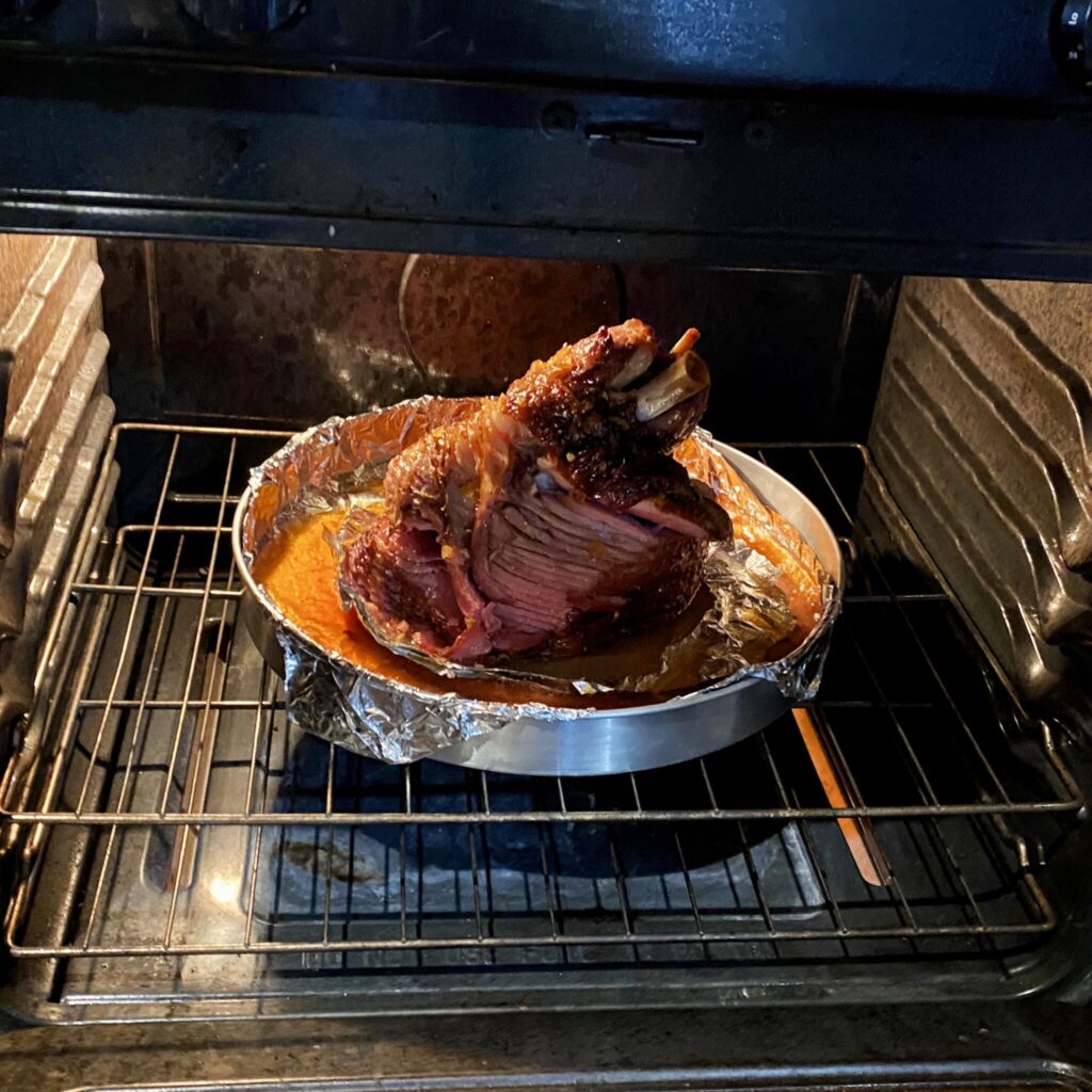 Returning the ham to the oven after glazing a second time with orange-bourbon ham glaze.