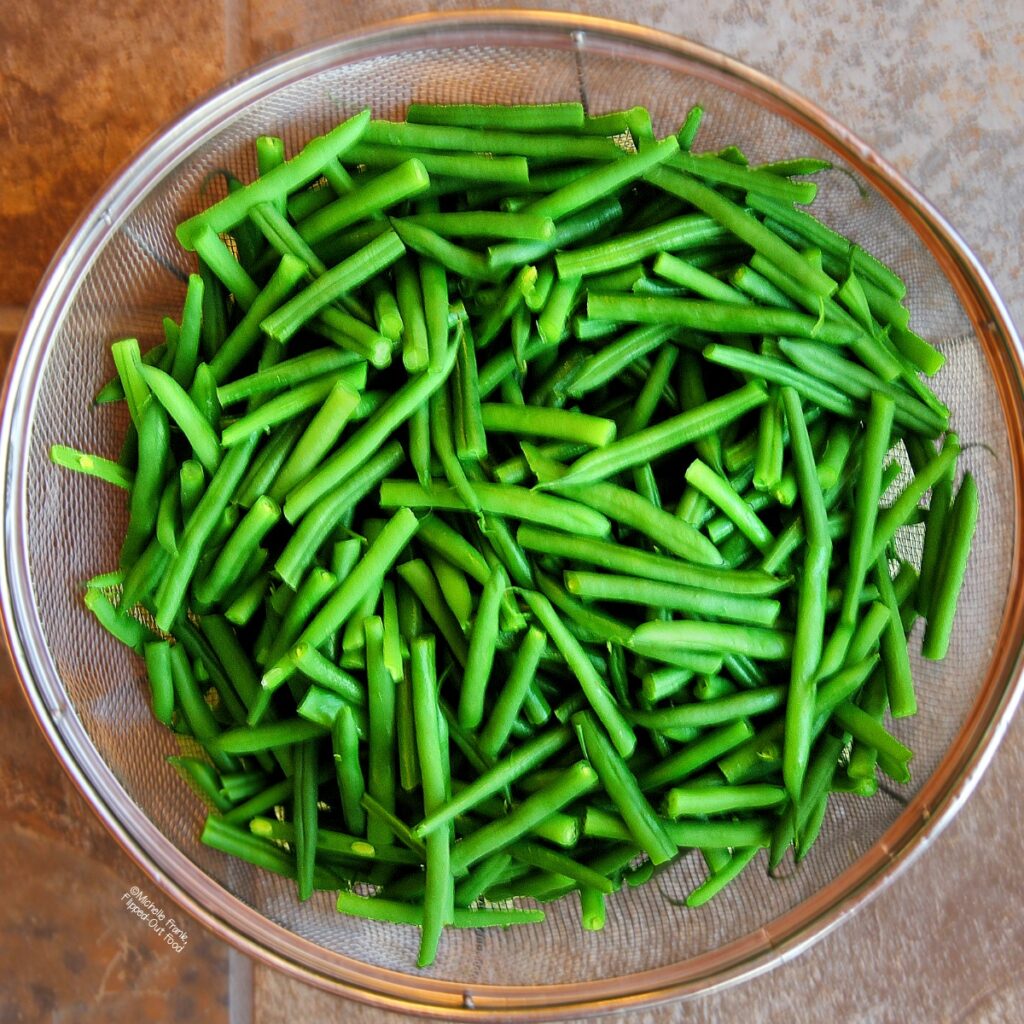 Haricots verts in a colander after blanching, ready for tangy 3-bean salad.