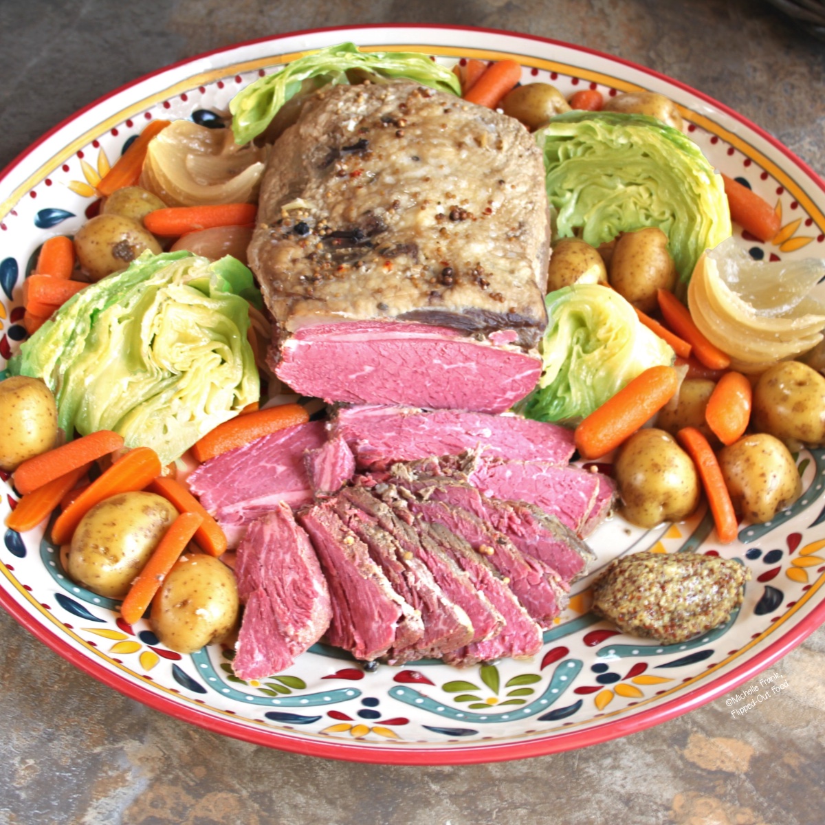 make-ahead crockpot corned beef and cabbage with potatoes and carrots on a large, decorative platter.