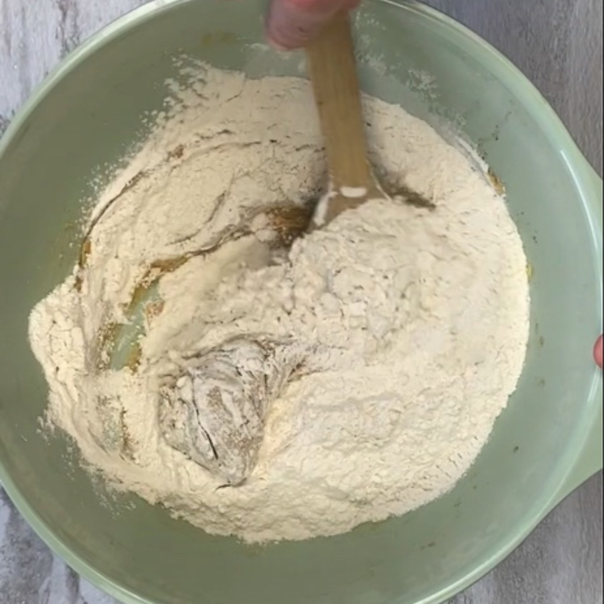 Overhead image of mixing bowl showing the flour being stirred into the butter sugar mixture