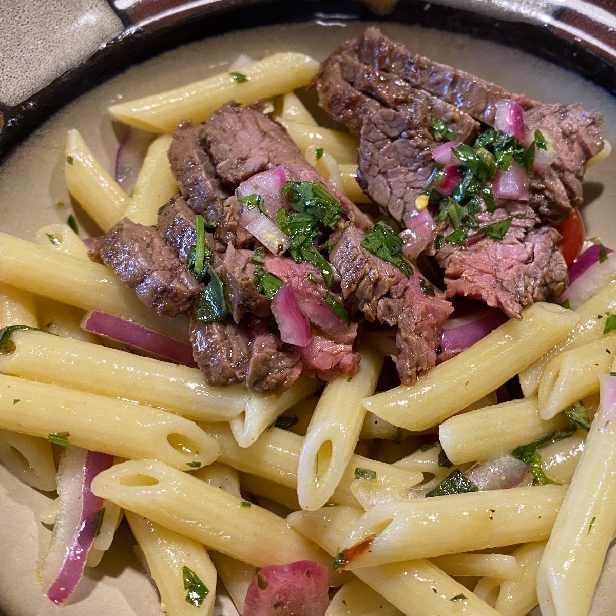 Chimichurri pasta salad topped with flank steak.