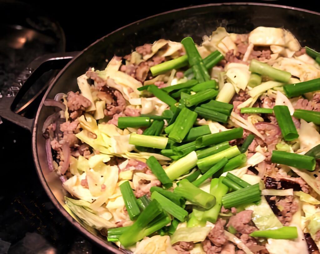 A wok filled with inside-out eggroll bowl ingredients.