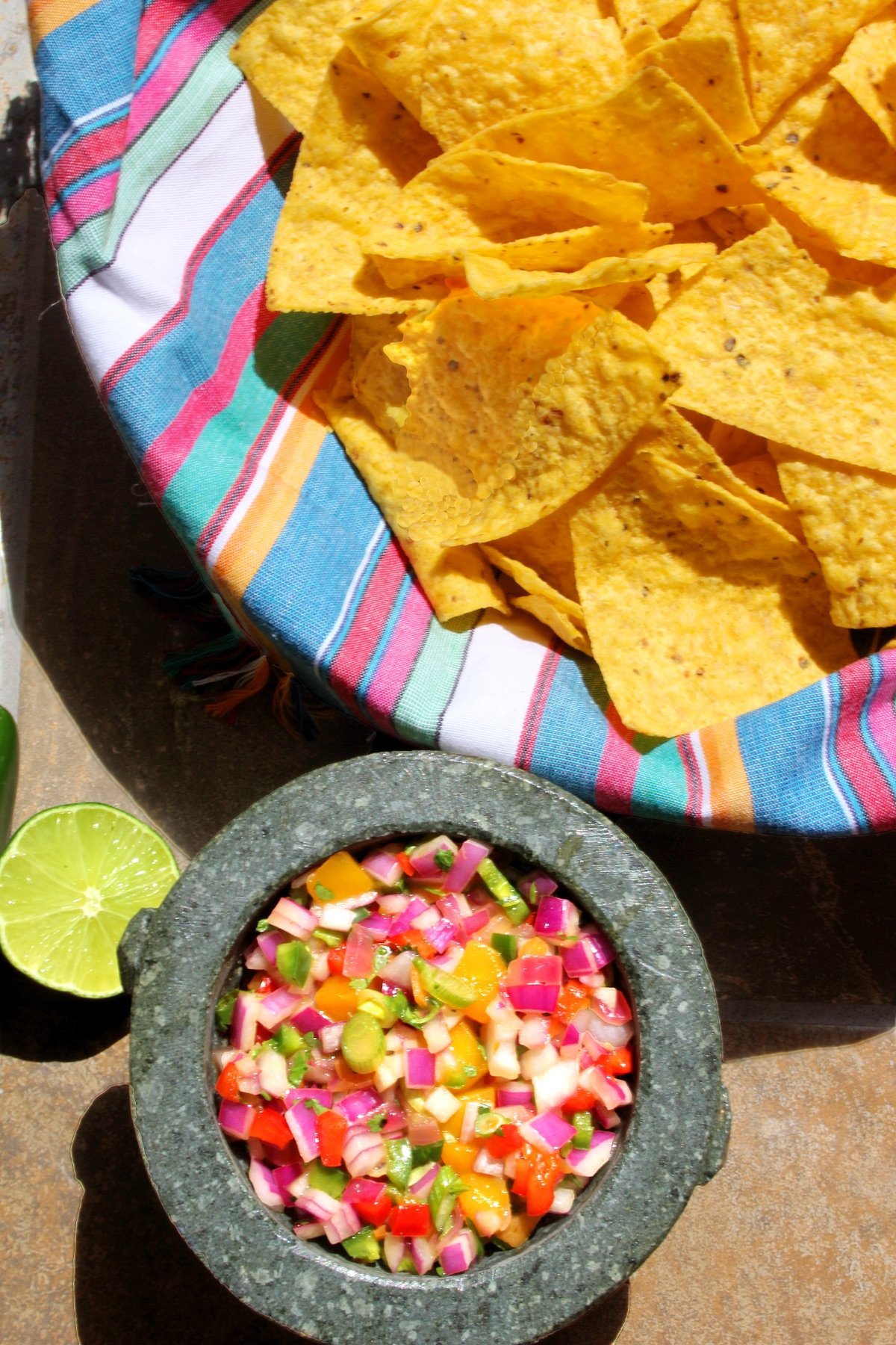 Fiery Mango-Habanero Salsa in a molcajete with tortilla chips and lime.