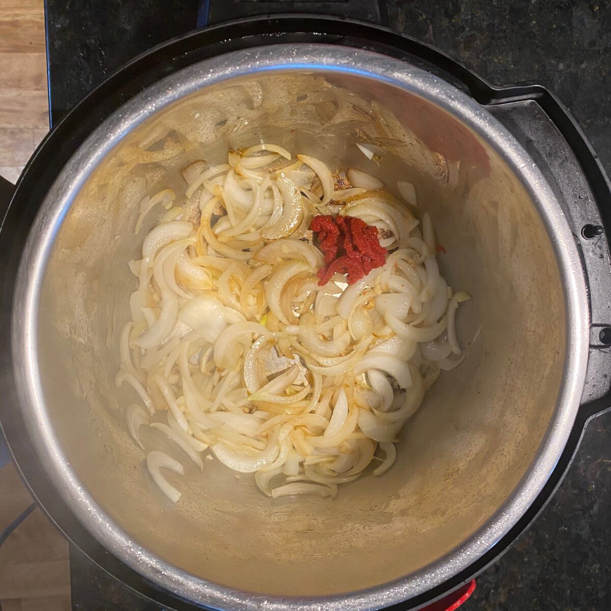 Adding tomato paste to the softened onions and garlic.