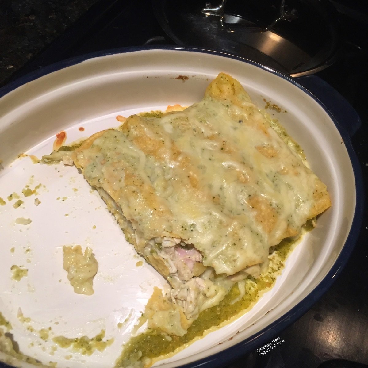 Half-eaten green chile turkey enchiladas in a baking dish.