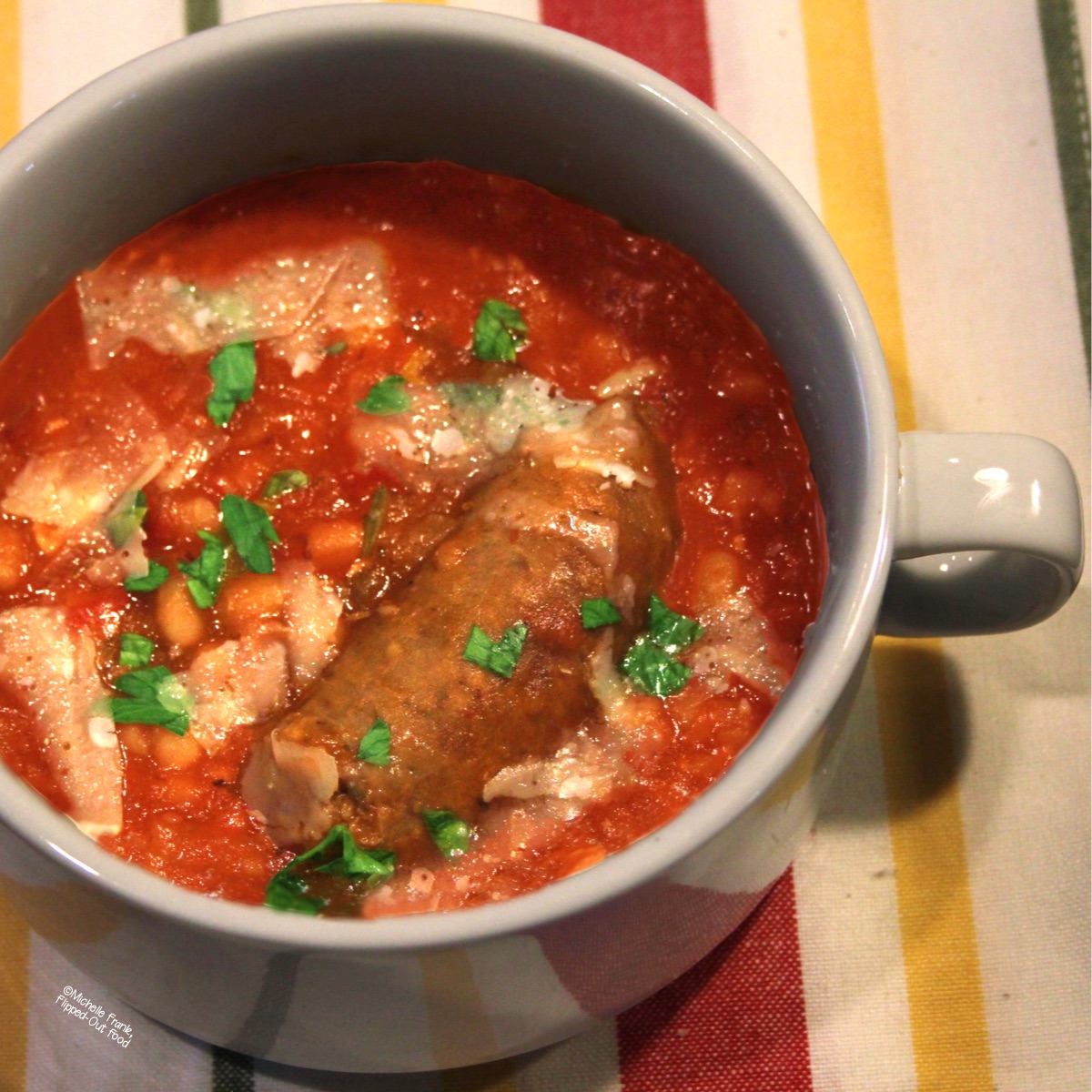 Italian Sausage and Beans (Salsiccie e Fagioli) in a white bowl with handles, garnished with chopped parsley.