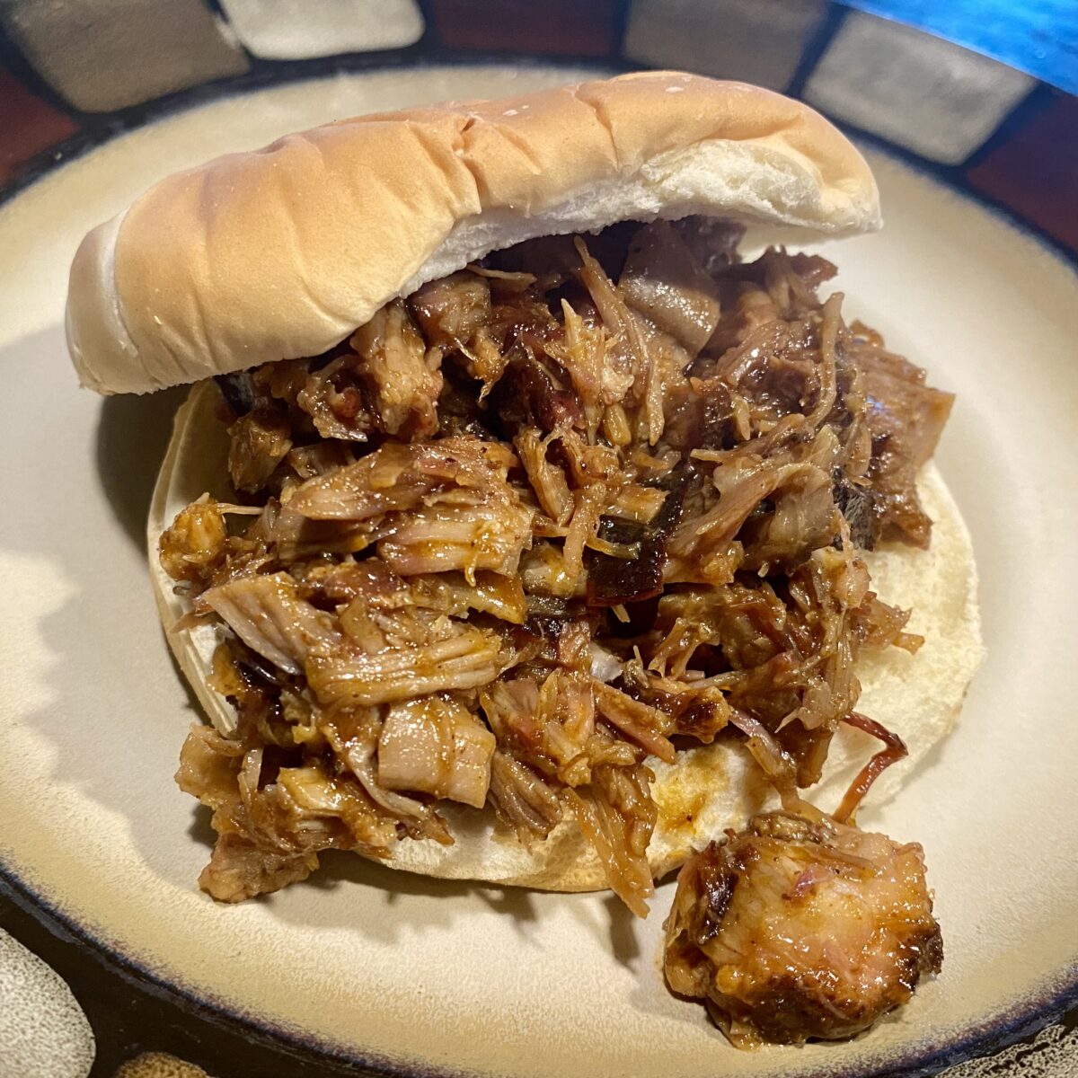 Close up view of pulled pork sandwich on white but on white plate.