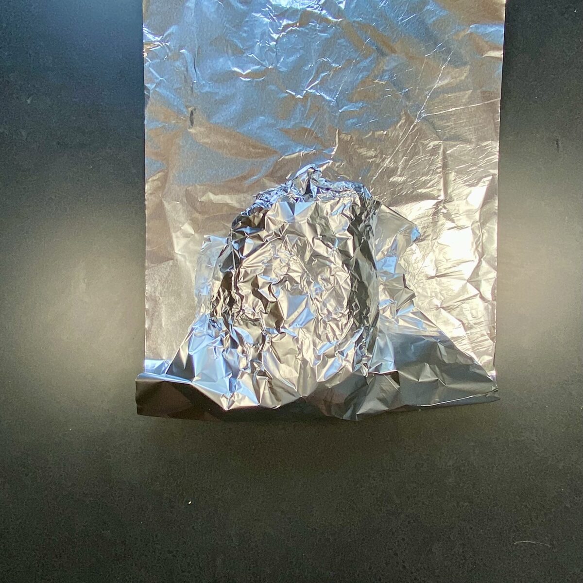 Top view of showing half of the second layer of tinfoil being wrapped around pork butt.