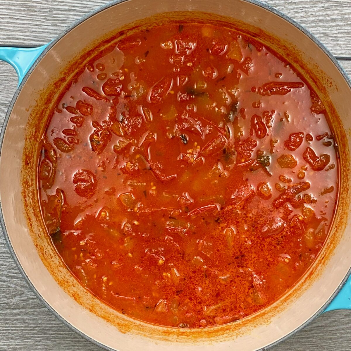 Top view of tomato soup after it has simmered looking like a rustic chunky tomato soup.