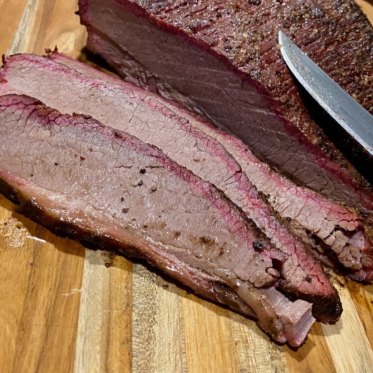 ¼ inch thick slices of smoked brisket on a cutting board.