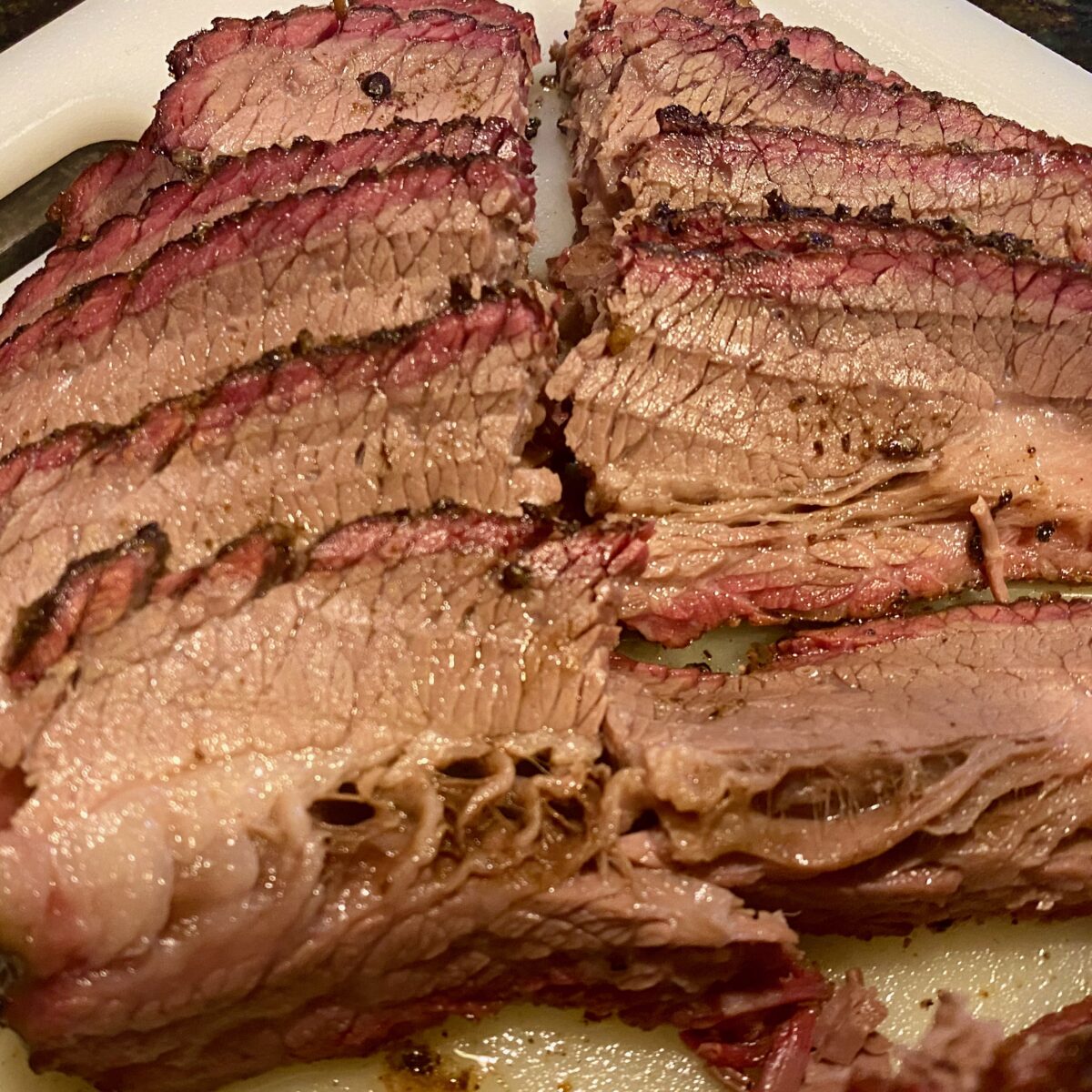 Close up view of sliced smoked brisket showing the smoke ring and juiciness of the meat.