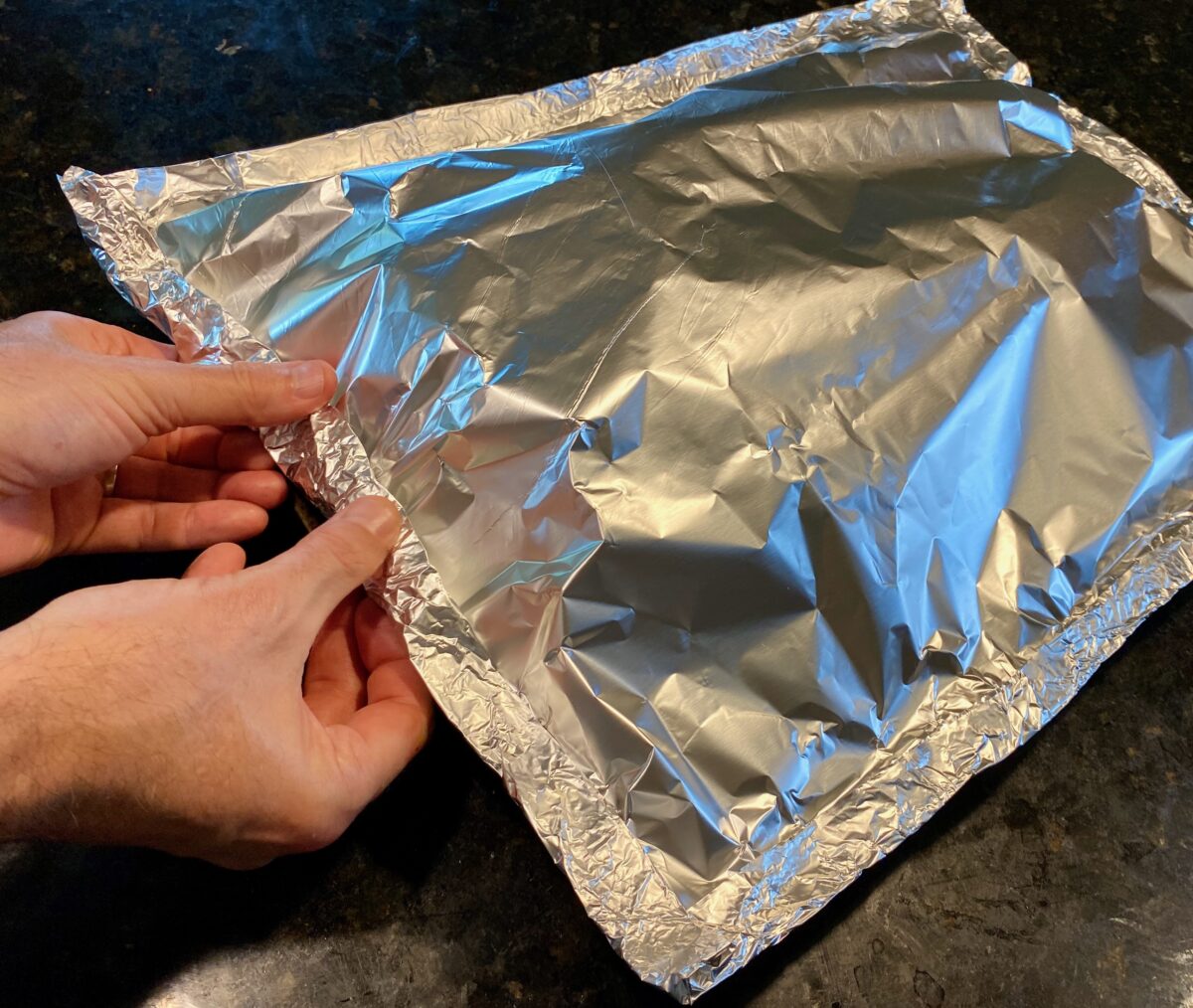 Image showing how to properly wrap the brisket by crimping the two sheets of tinfoil together creating an airtight seal.