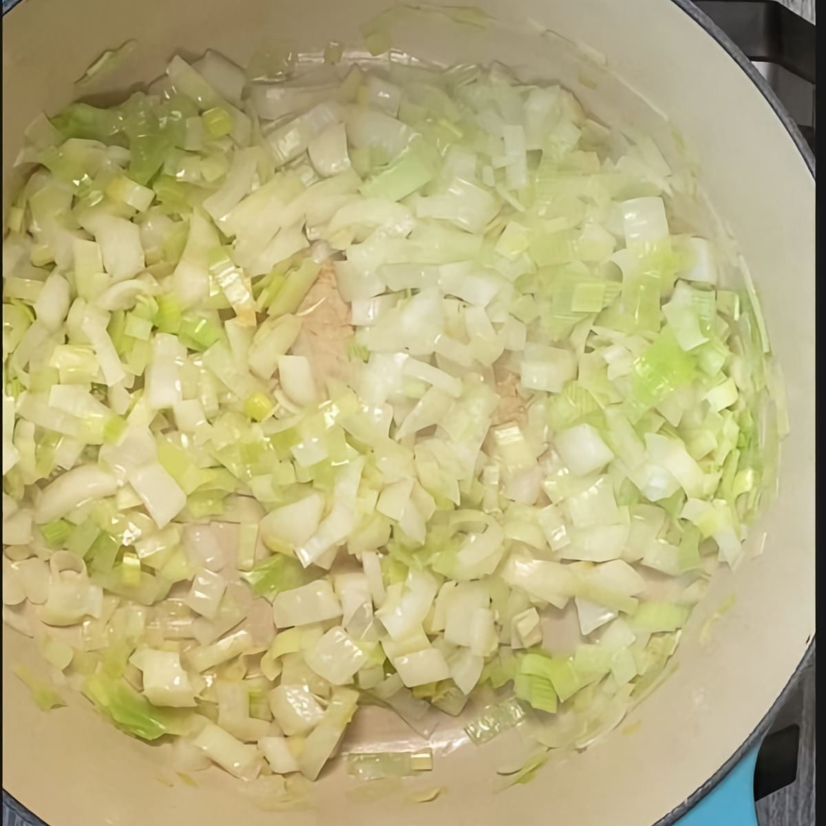 Top view of leeks and onions sautéing in butter. 
