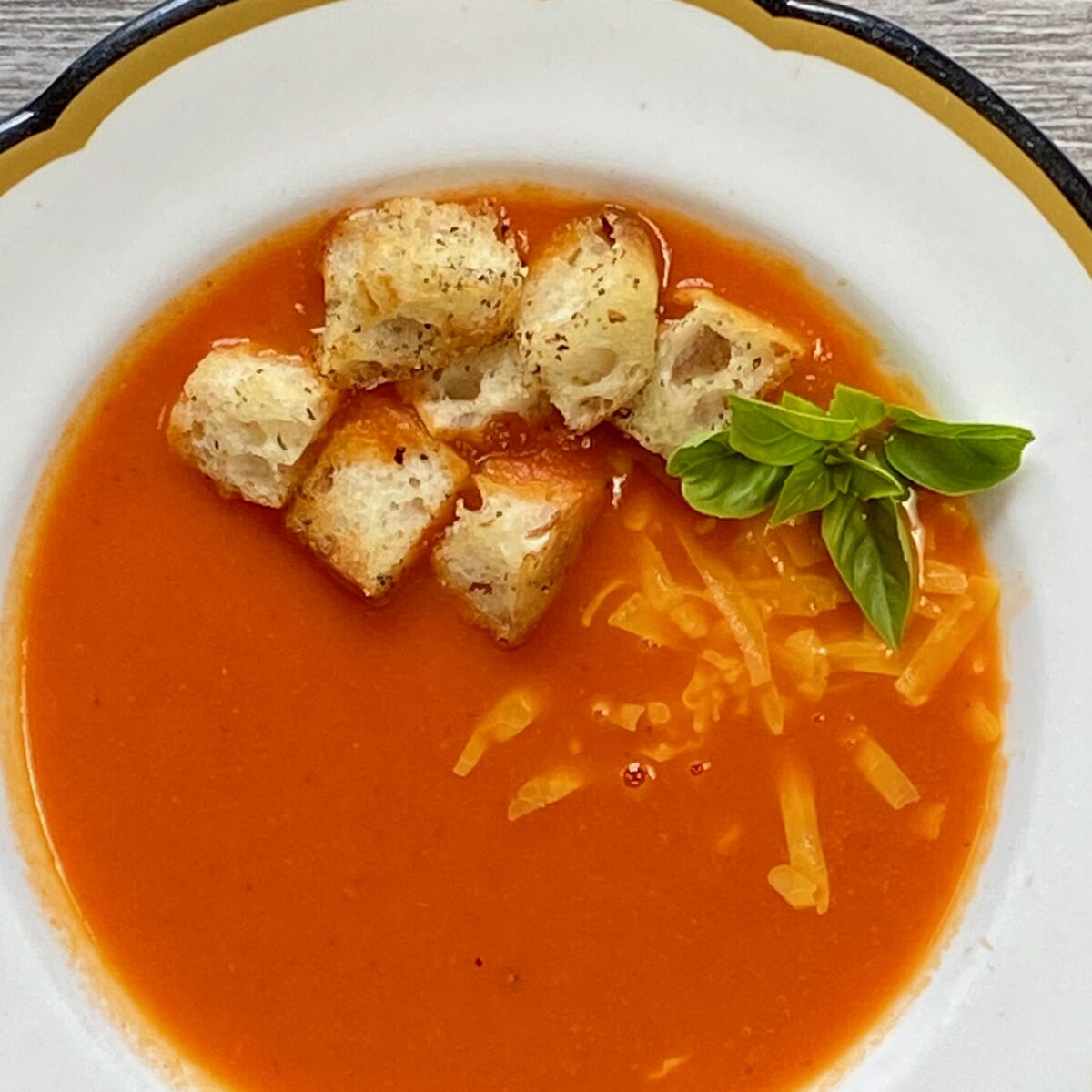 Overhead view of tomato soup with homemade croutons placed on top.