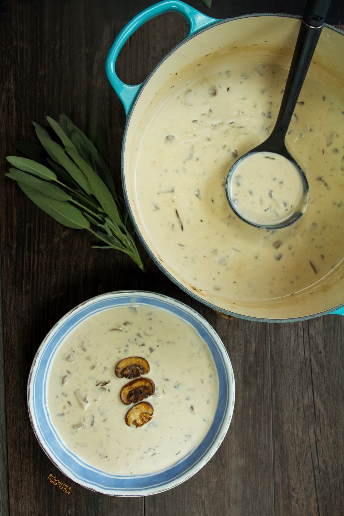 A pot of homemade cream of mushroom soup with a full ladle sits next to a blue and white bowl with a serving of the soup. The soup has been topped with three golden-brown mushroom slices.