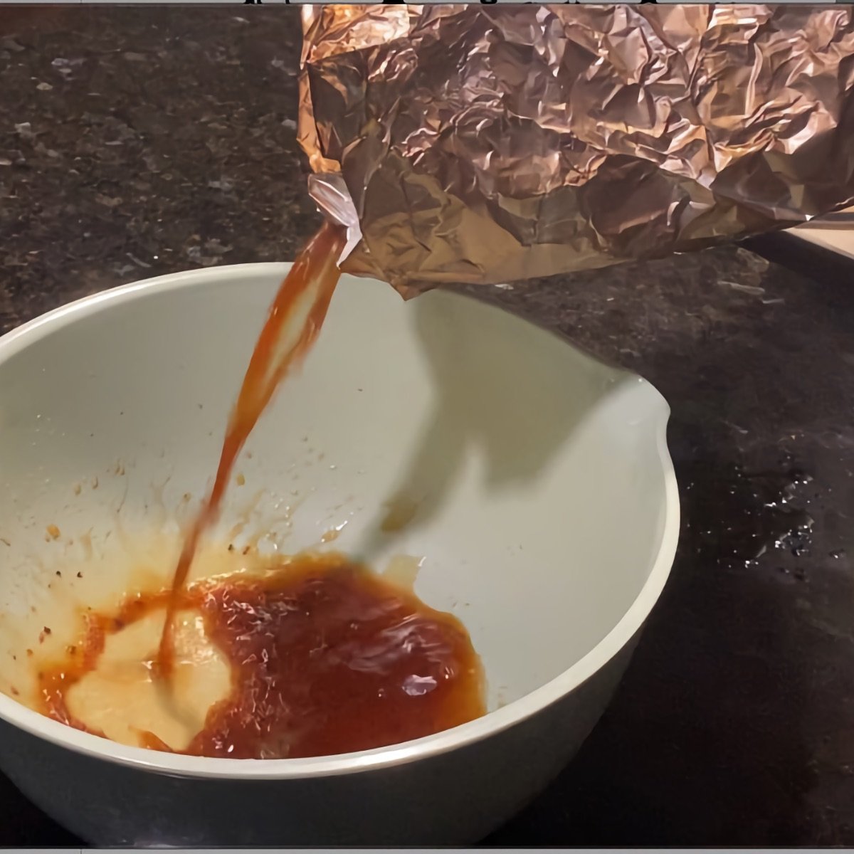 Pouring brisket juice from the foil-wrapped brisket into a bowl.