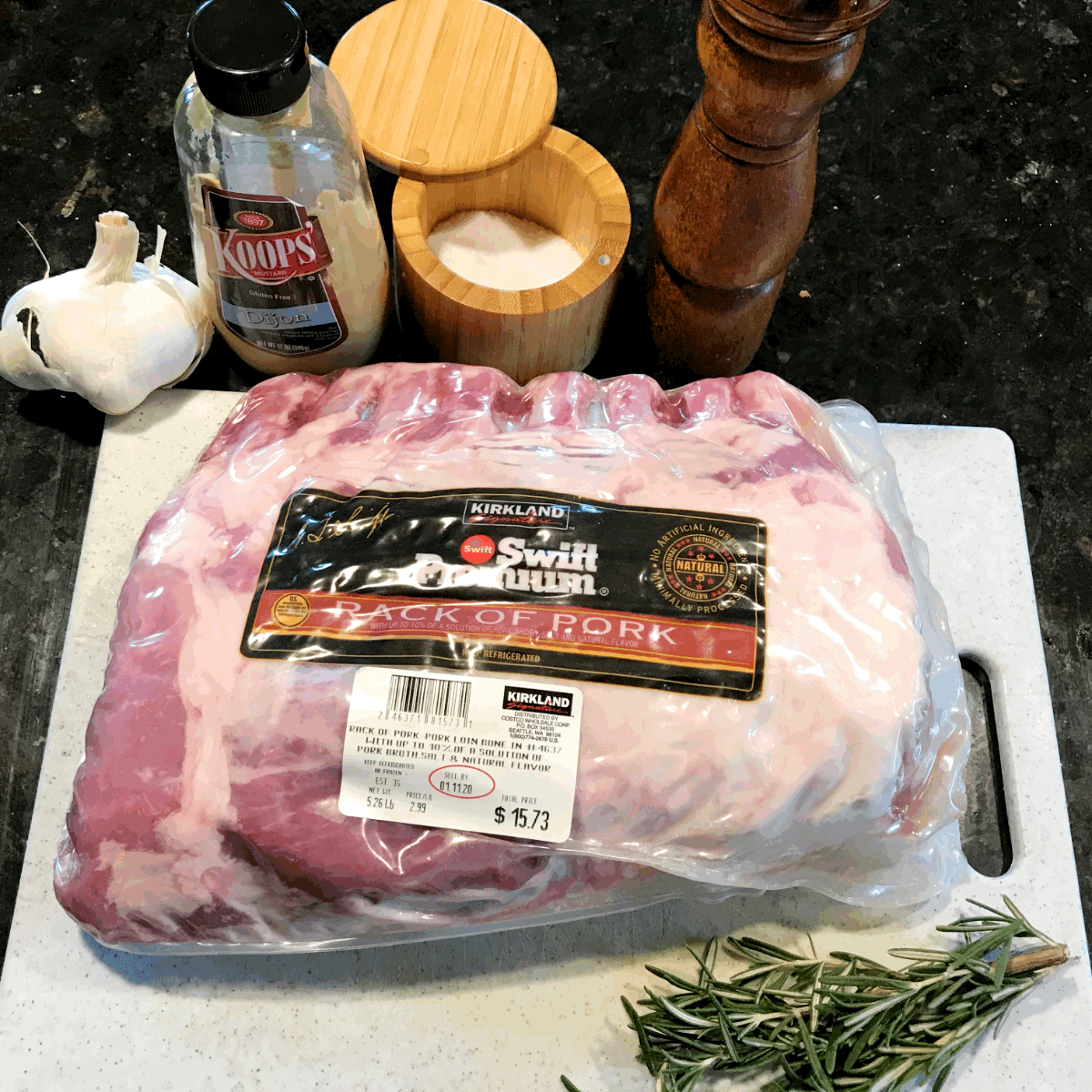 Overhead view of Costco rack of pork still in packaging on a cutting board with various pork rub ingredients all around it.